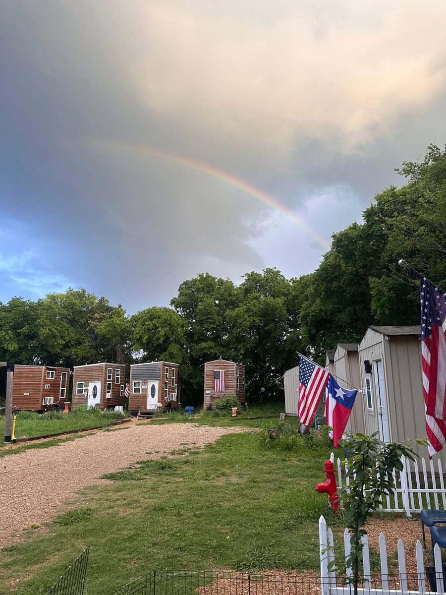 Serenity Veterans Village grounds under a rainbow with flags